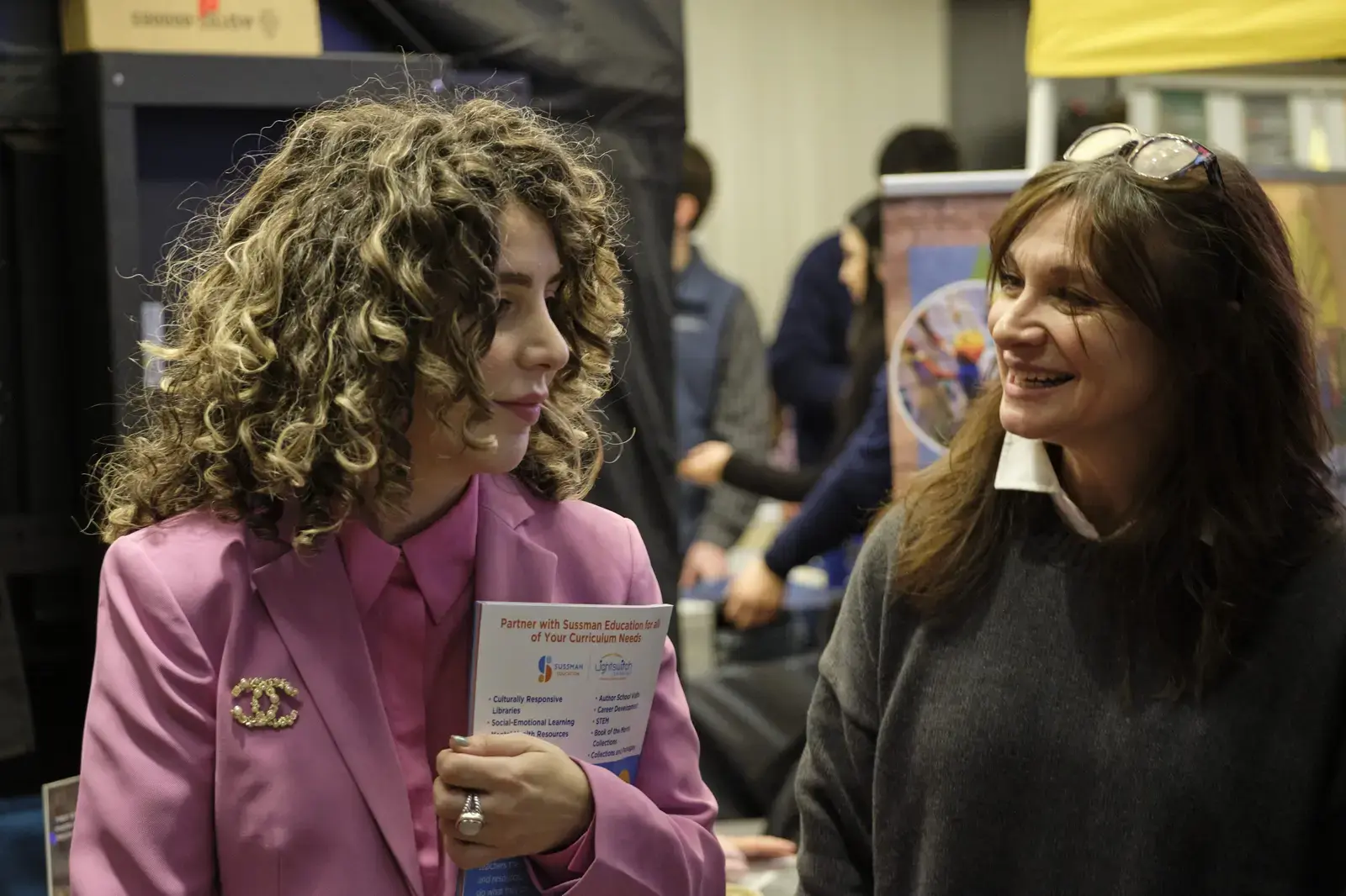 Two women conversing at school education fair event