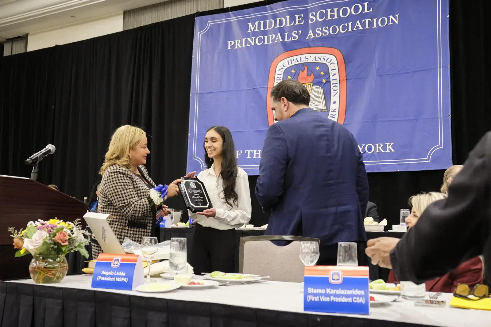 Student receives award plaque at Middle School Principals Association event