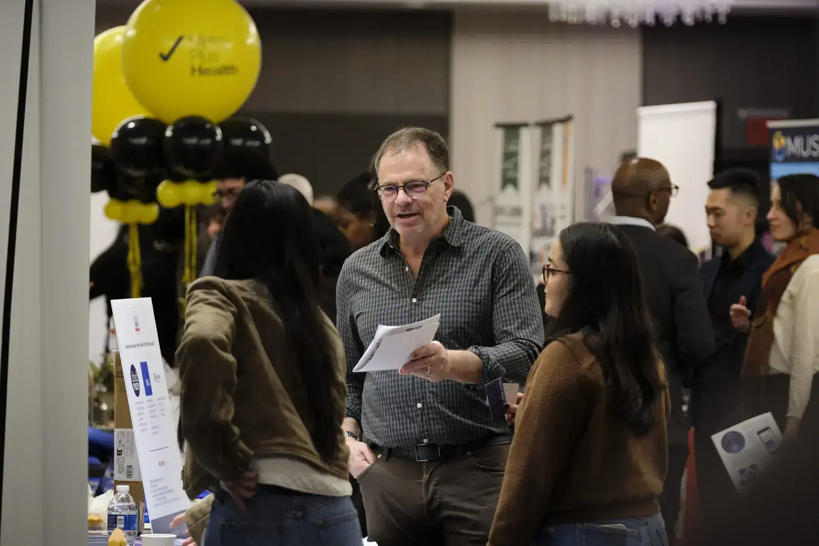 Staff member speaking with students at college fair event