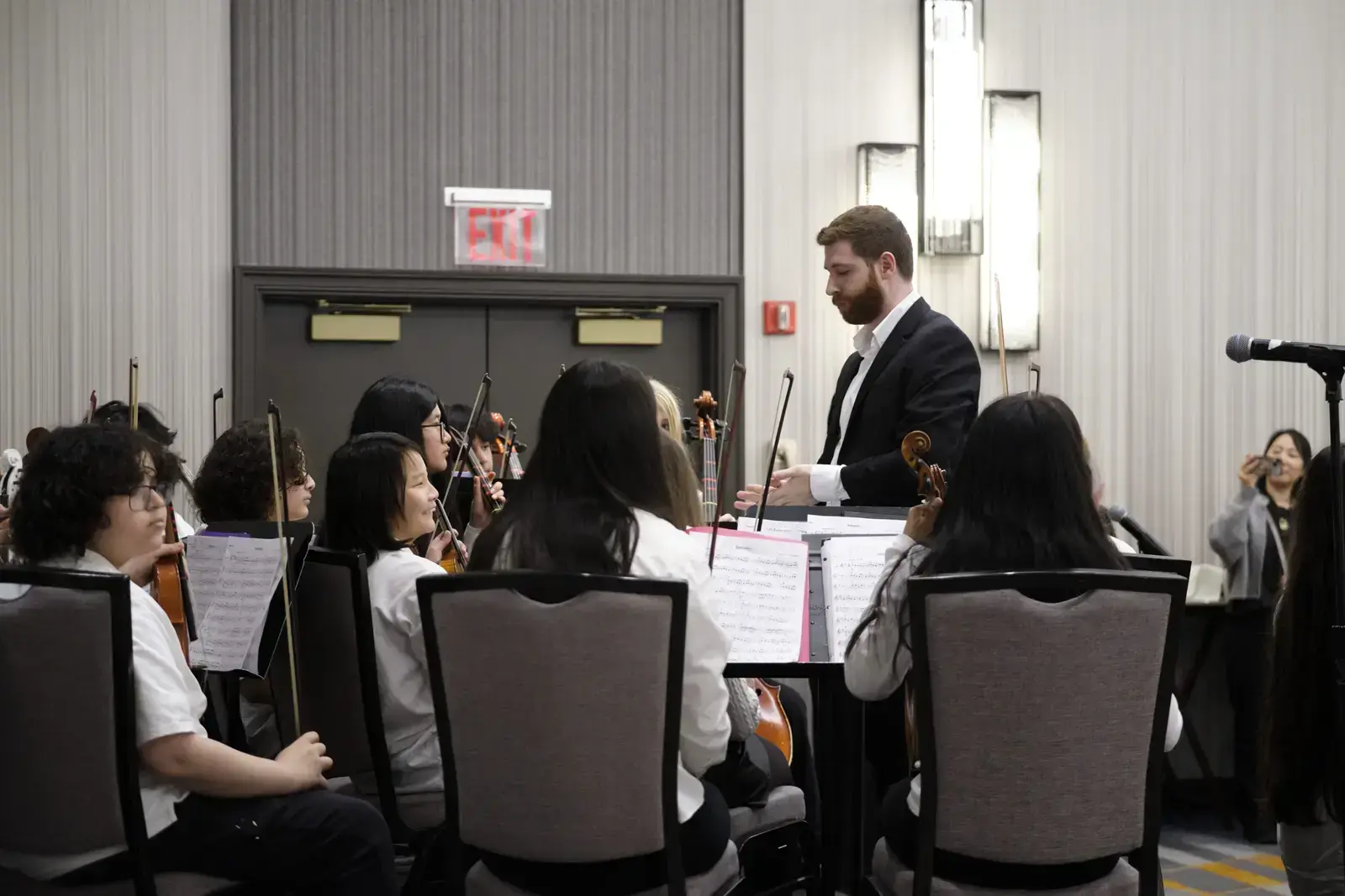 Conductor leading student orchestra during rehearsal