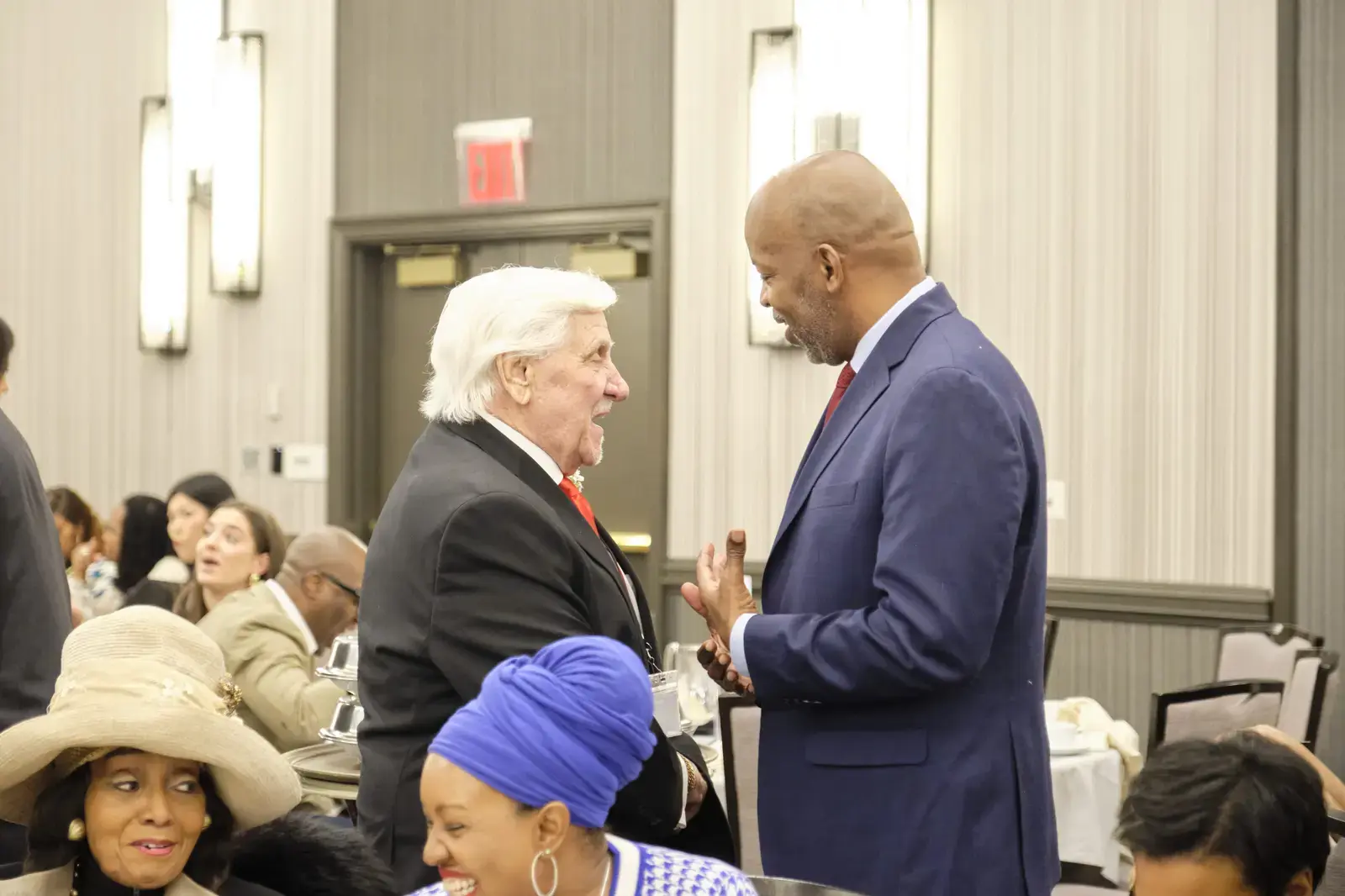 Two men in suits conversing at a community event