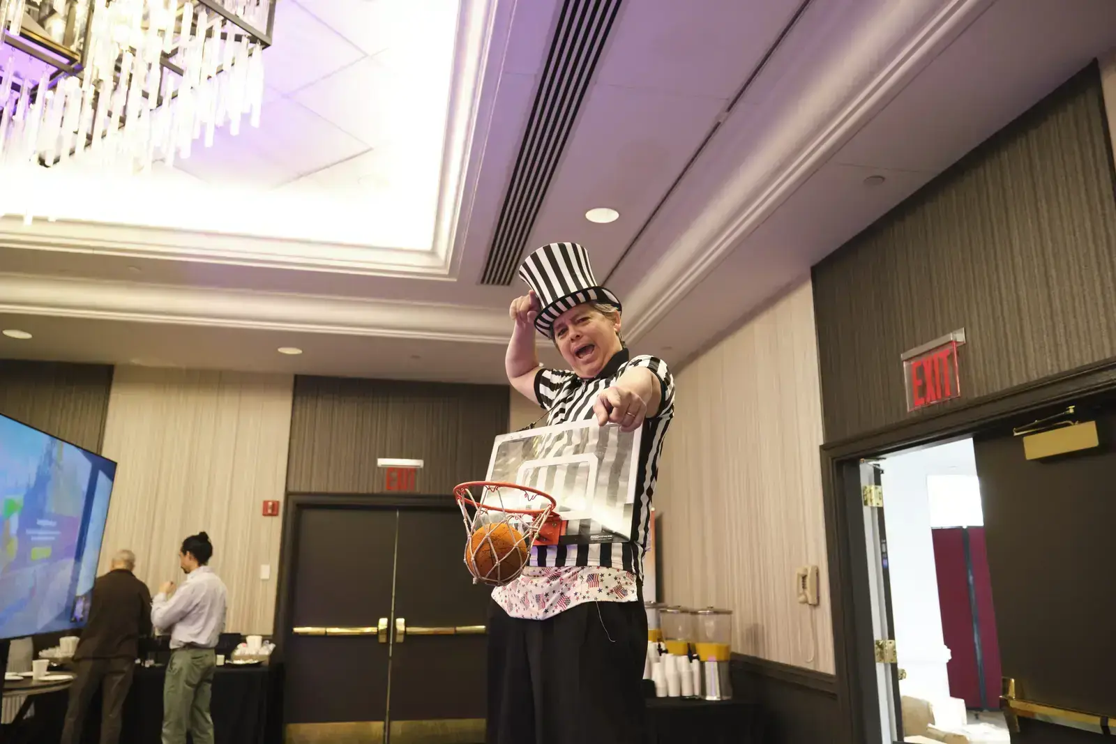 Student dunking basketball while wearing striped referee costume