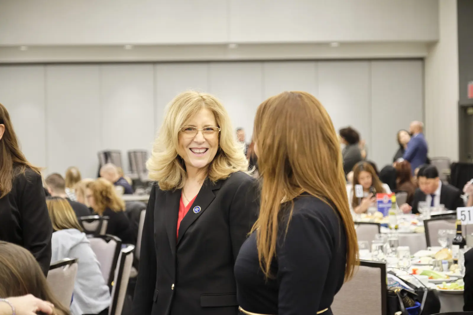 Two women in business attire conversing at professional event