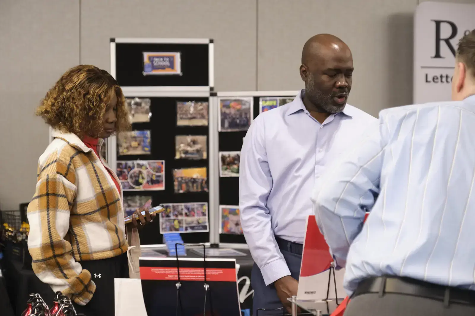 Three people reviewing materials at school information display table