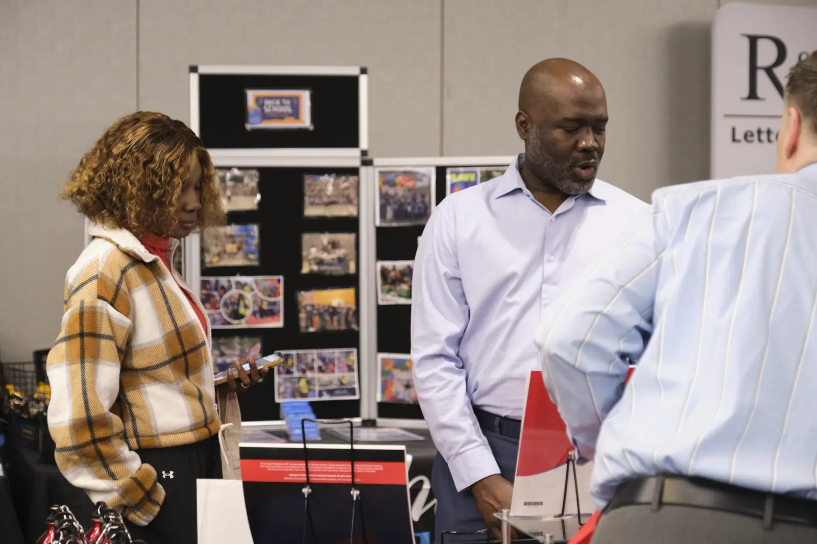 Three people reviewing materials at school information display table