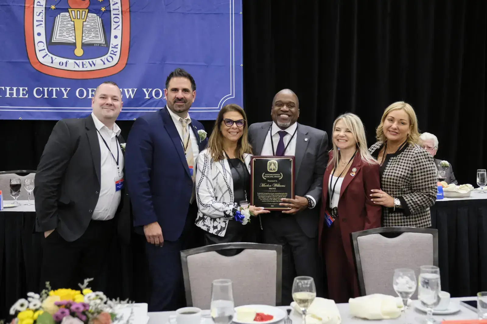 Six people posing with award plaque at City of New York event