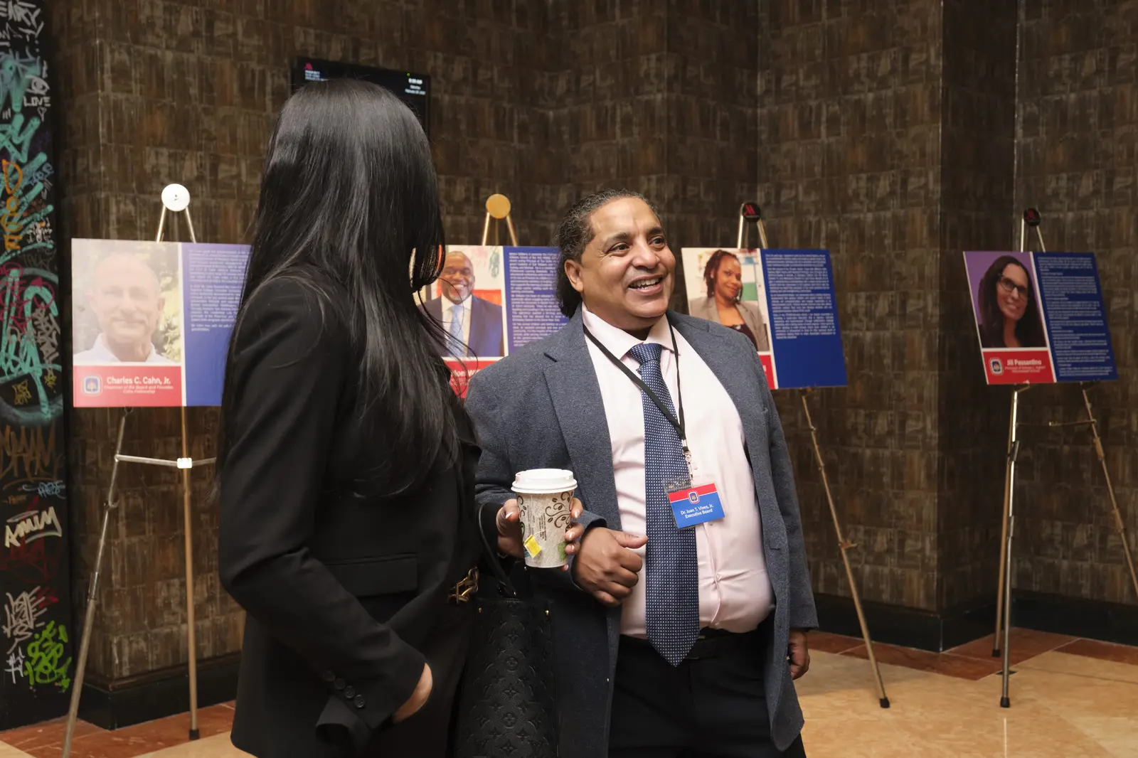 Two attendees conversing at exhibition display with biographical posters