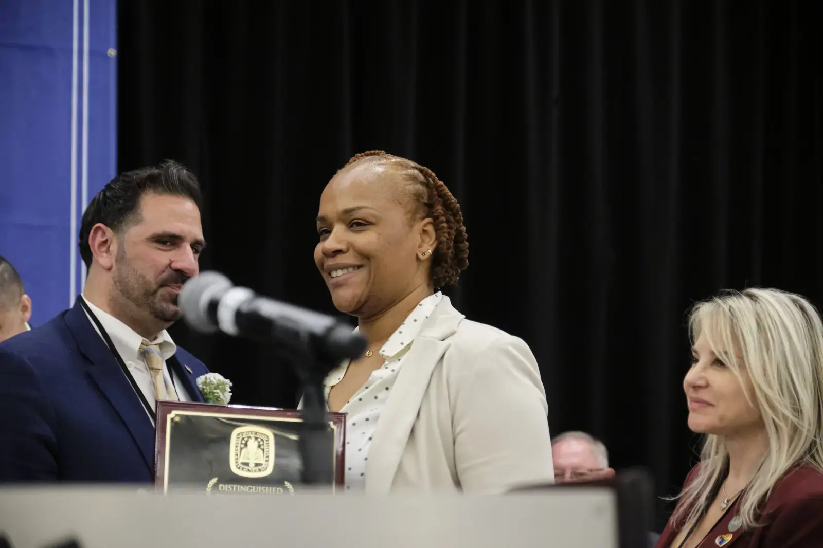 Award recipient smiling while holding distinguished service plaque at ceremony