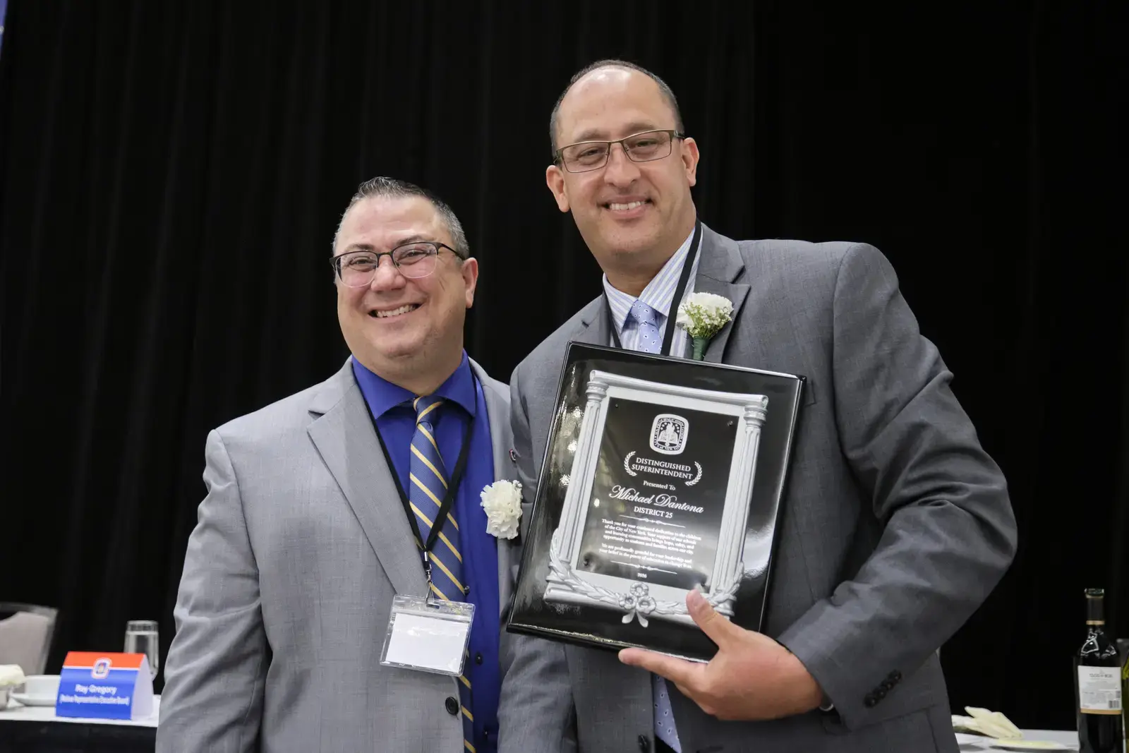 Two men holding award plaque at recognition ceremony
