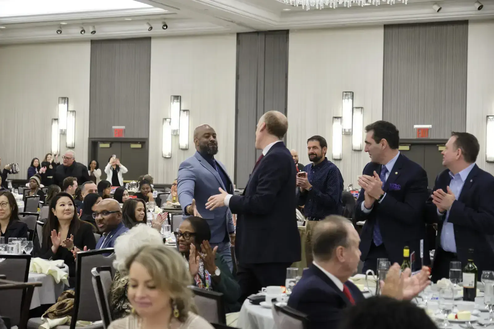Award recipient shaking hands while attendees applaud at banquet