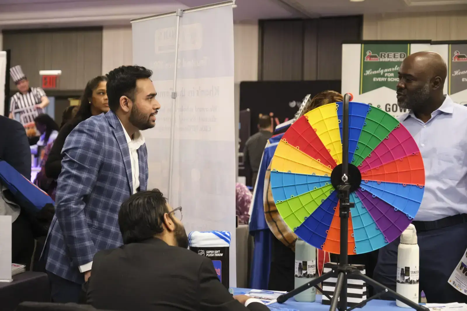 Attendees gathered around colorful prize wheel at career fair booth