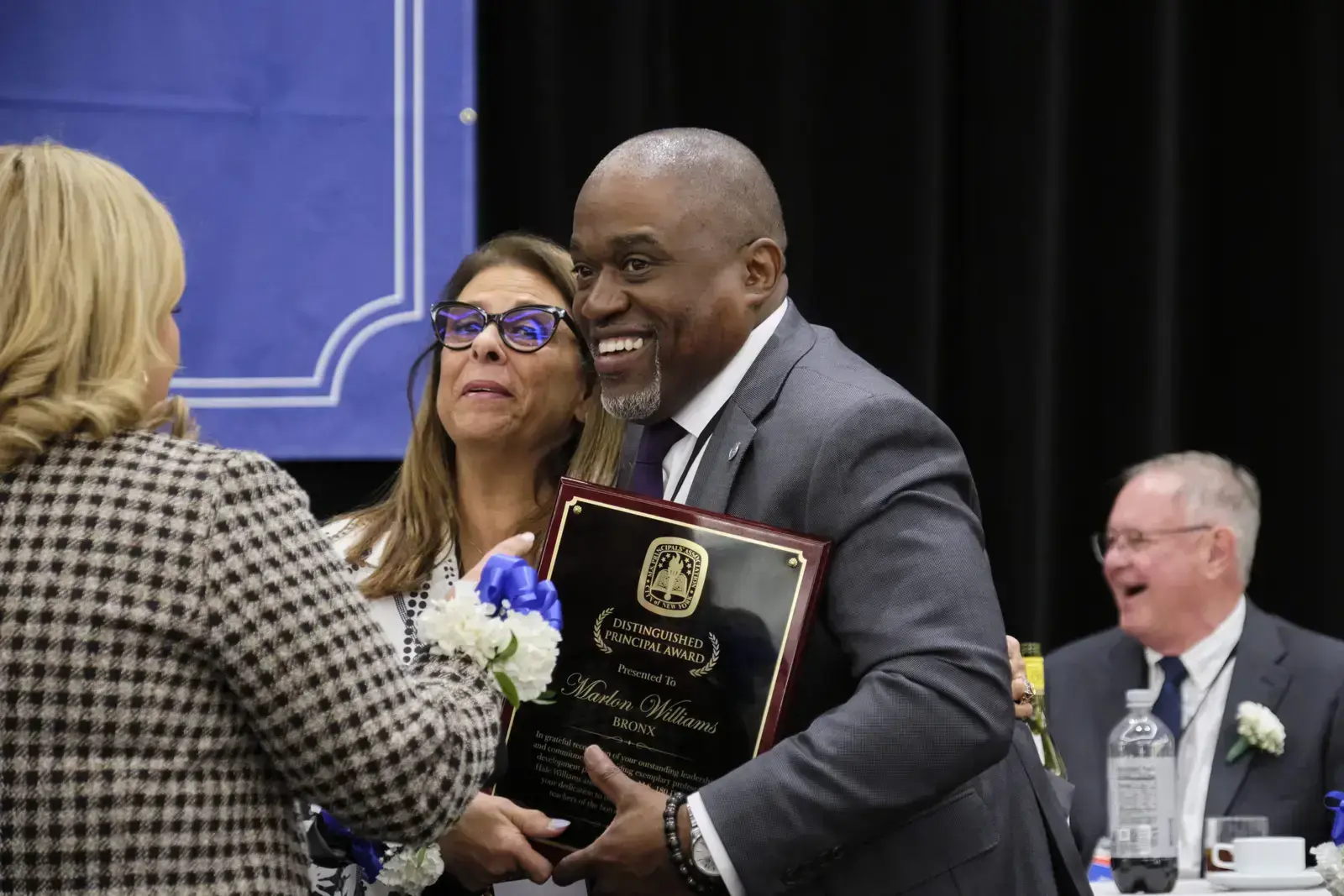 Award recipient smiling while holding Distinguished Principal Award plaque