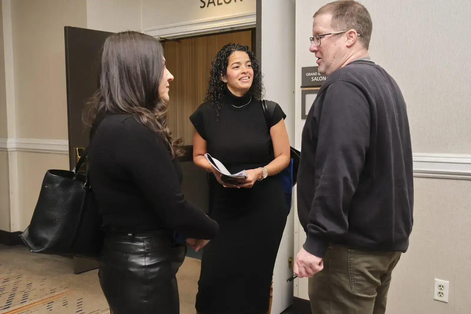 Staff member greeting two visitors in school hallway