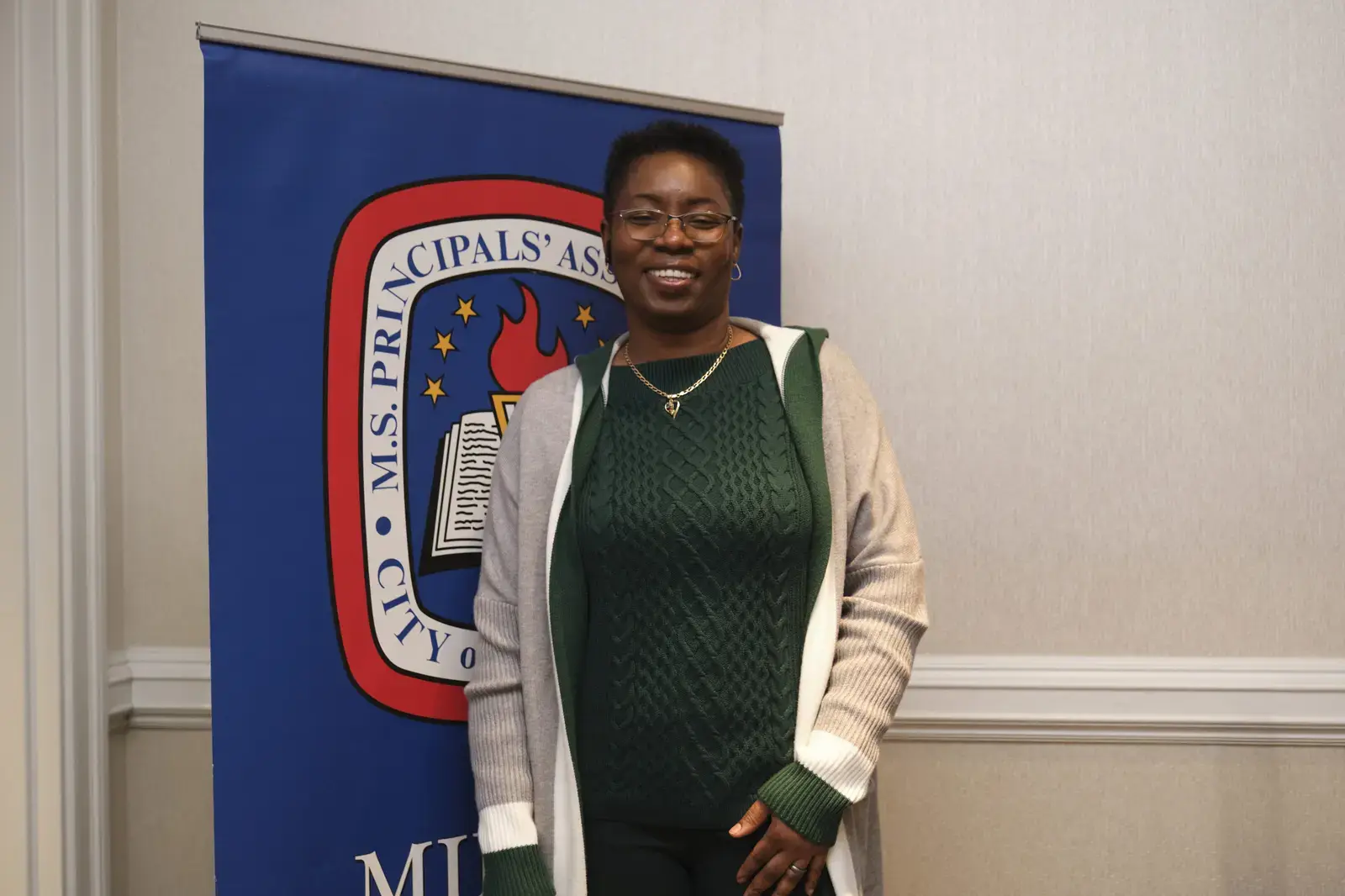 Staff member smiling in front of school banner