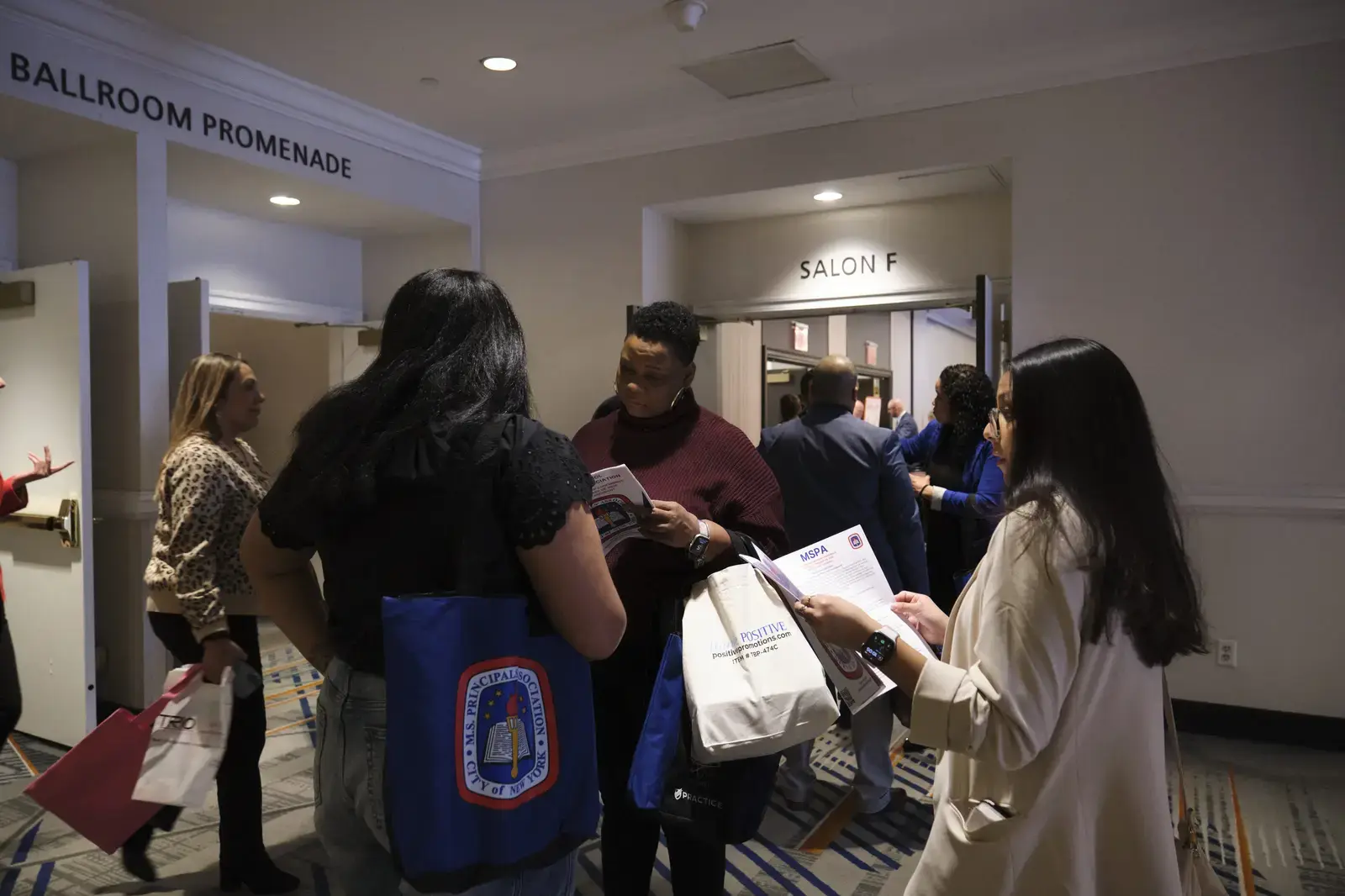 Students networking with information materials in conference hallway