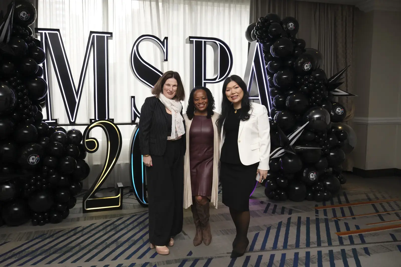 Three women pose at MSPA 2024 event with balloon decorations