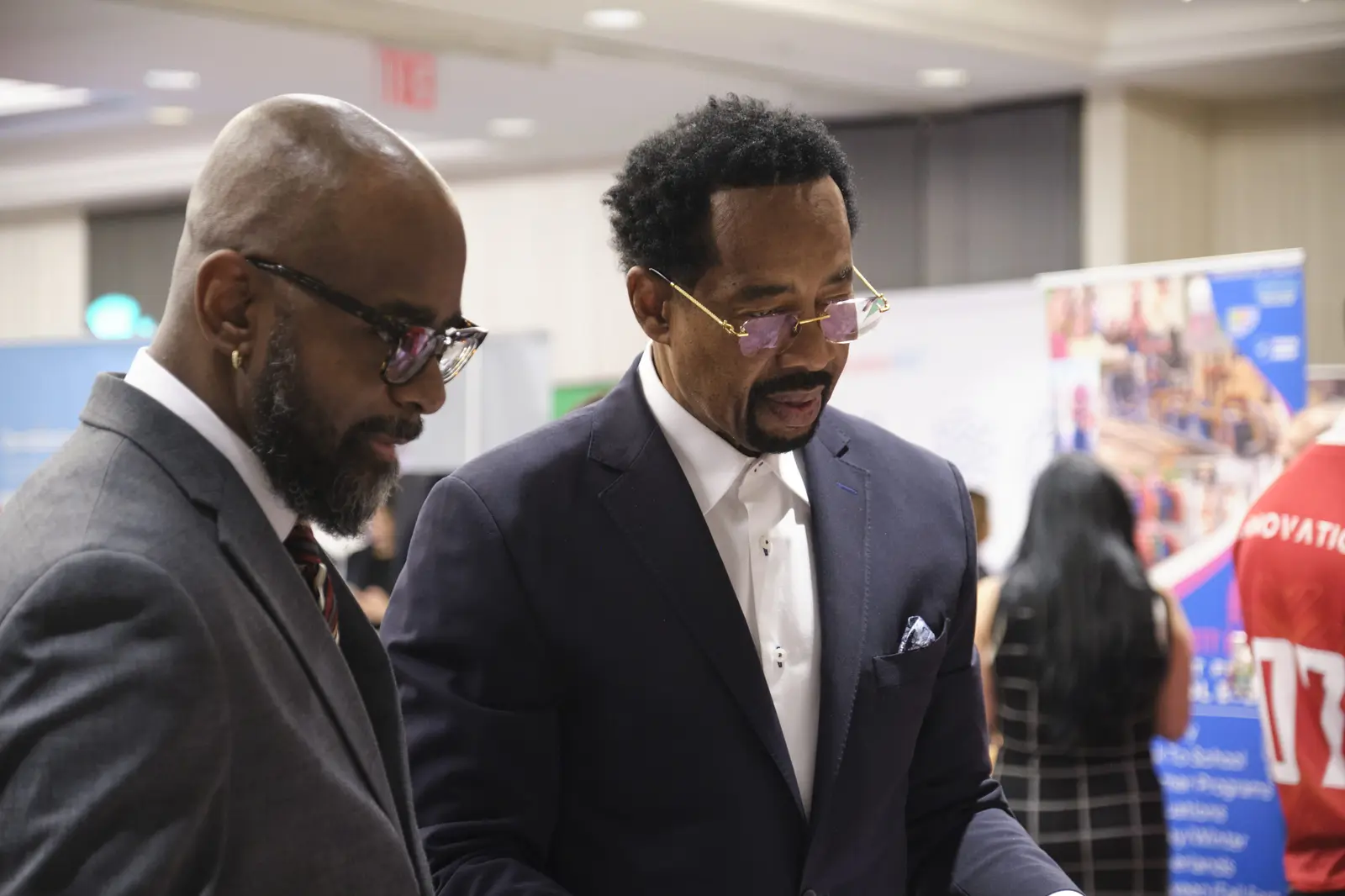 Two men in suits reviewing materials at school event