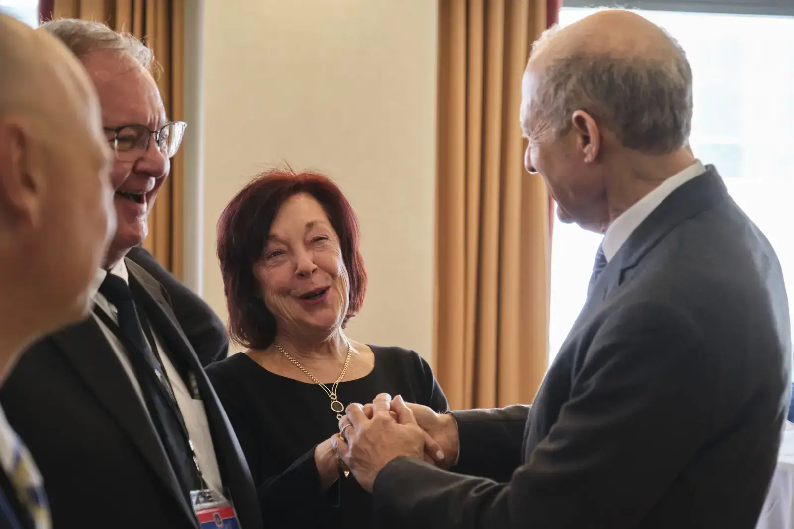 Four people in formal attire greeting each other warmly