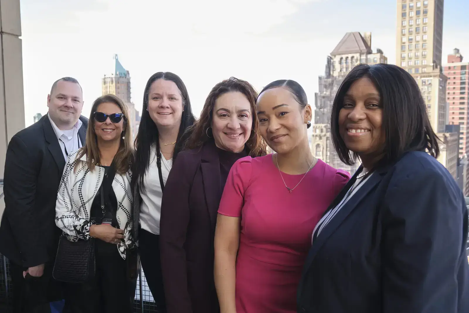 Six professional staff members posing together with city skyline backdrop