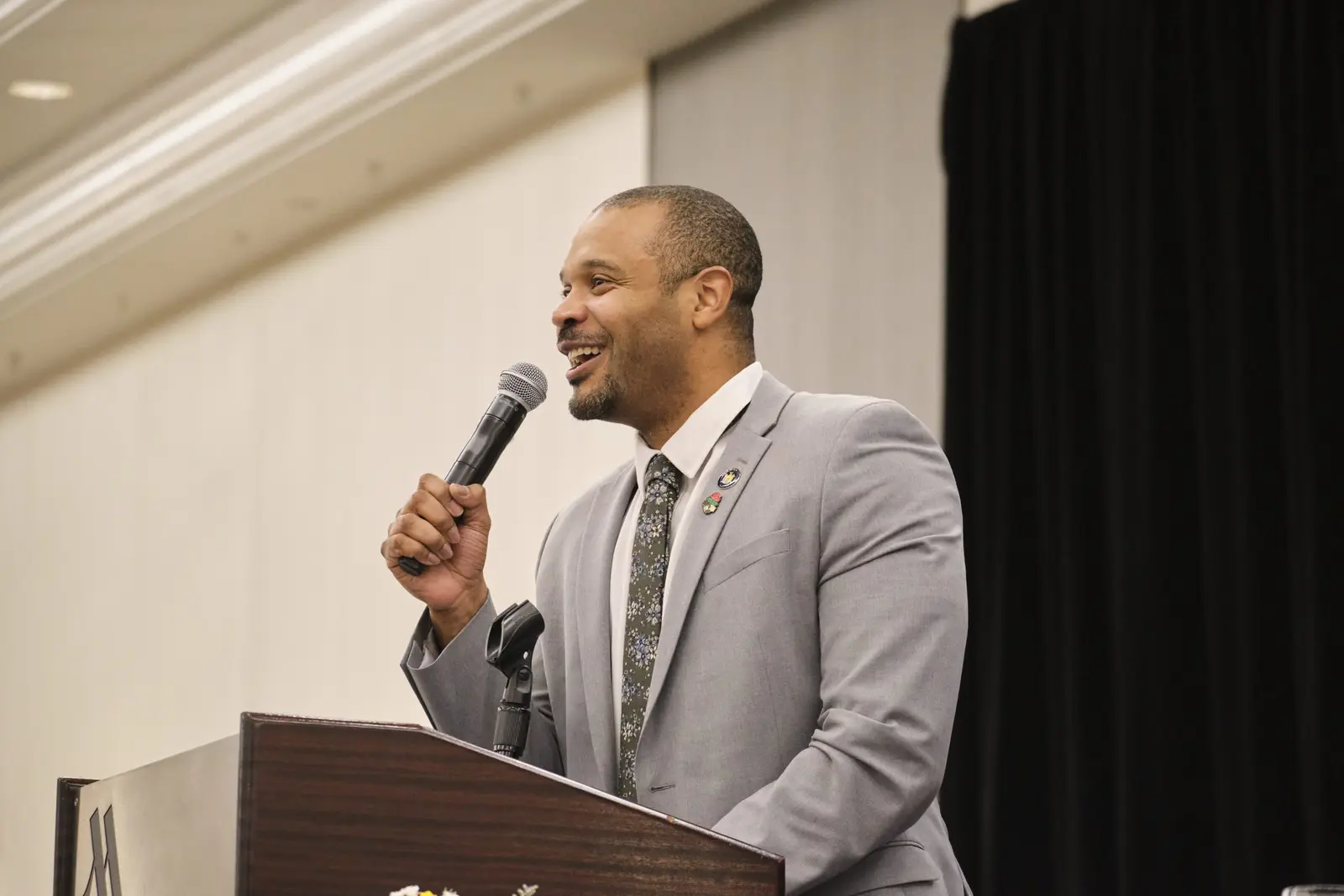 Speaker in gray suit presenting at podium with microphone