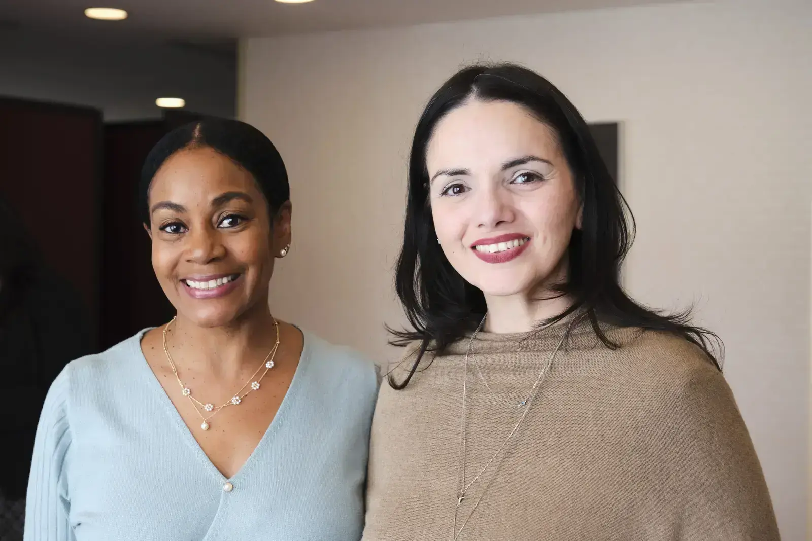 Two smiling staff members posing together in office