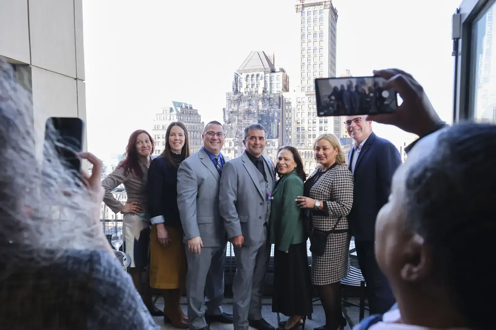 Group of seven professionals posing for photo on city rooftop