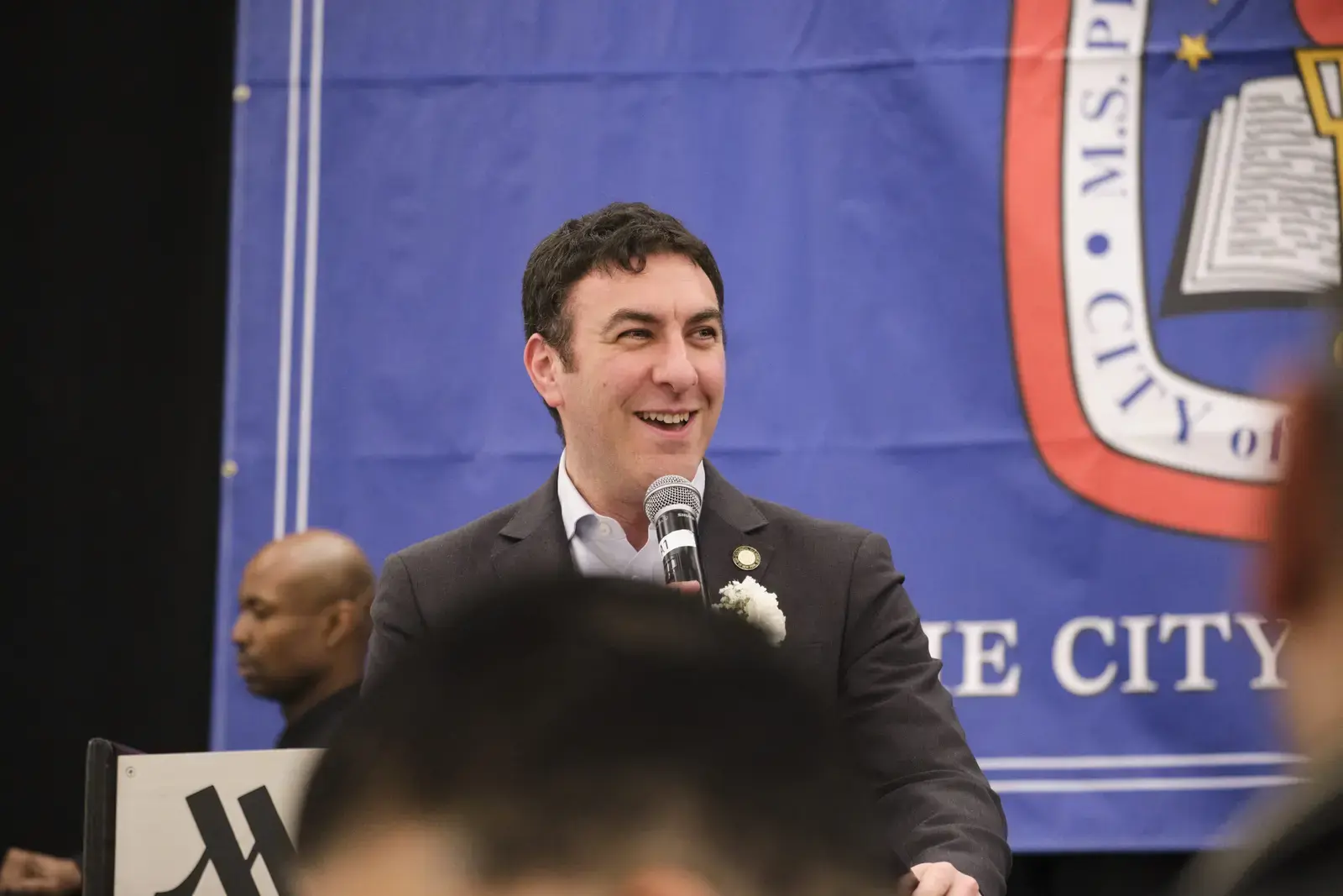 Speaker addresses audience at school event with microphone