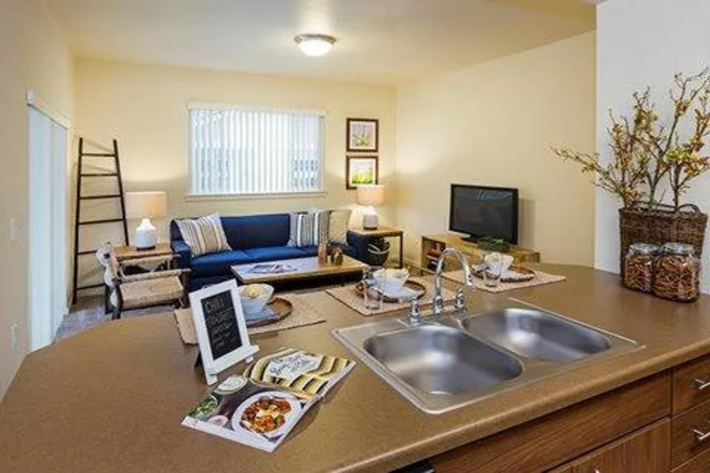 Kitchen with sink and view of living area with sofa, coffee table and tv