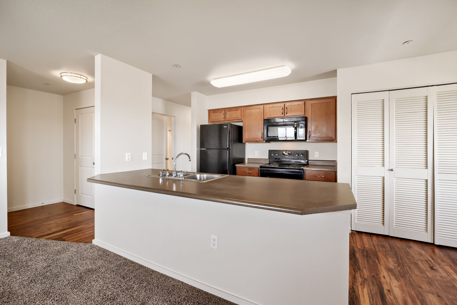 kitchen featuring wood cabinetry, black appliances, ample counter space, and breakfast bar seating.