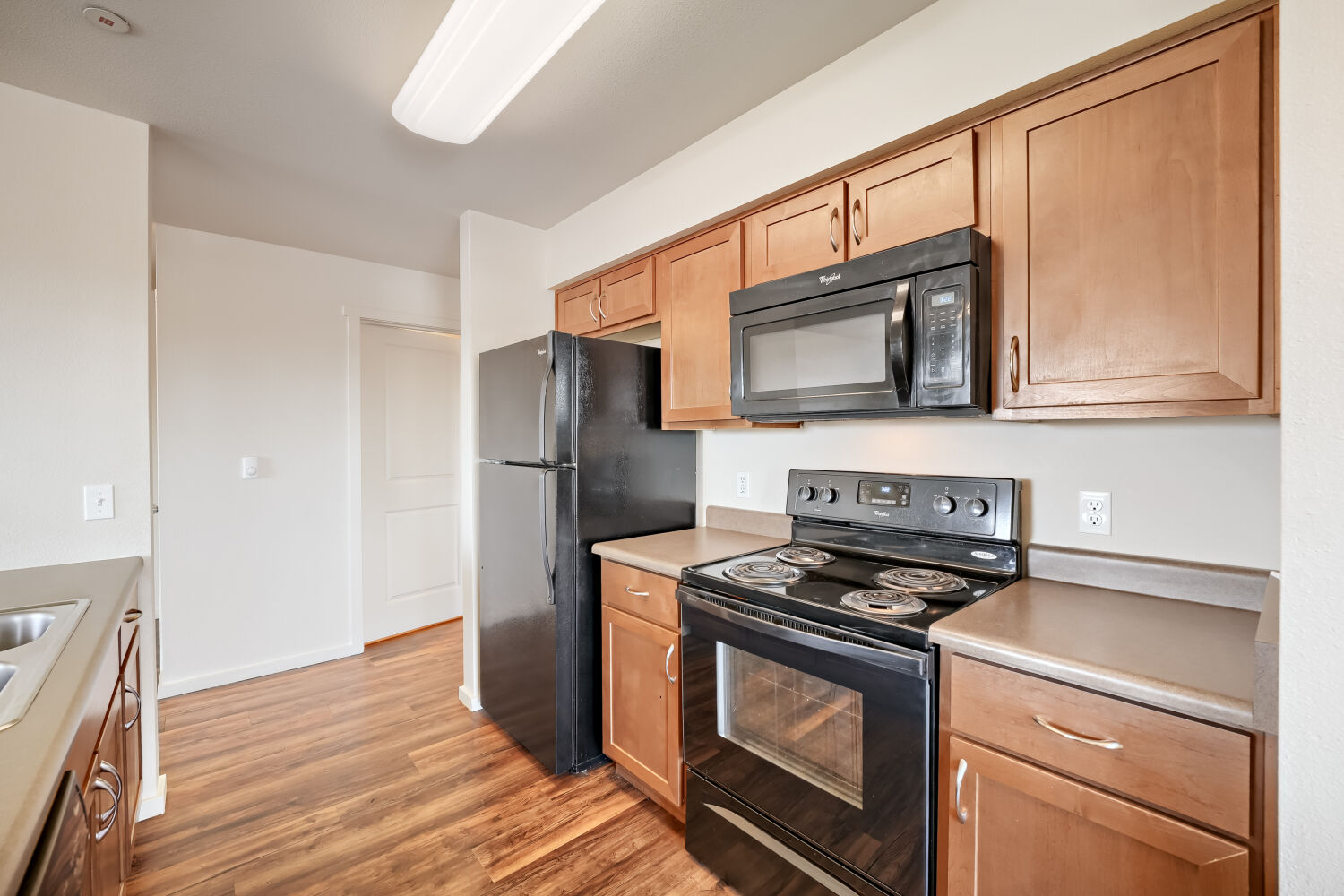 Apartment kitchen with black appliance package, wood cabinetry, and durable countertops