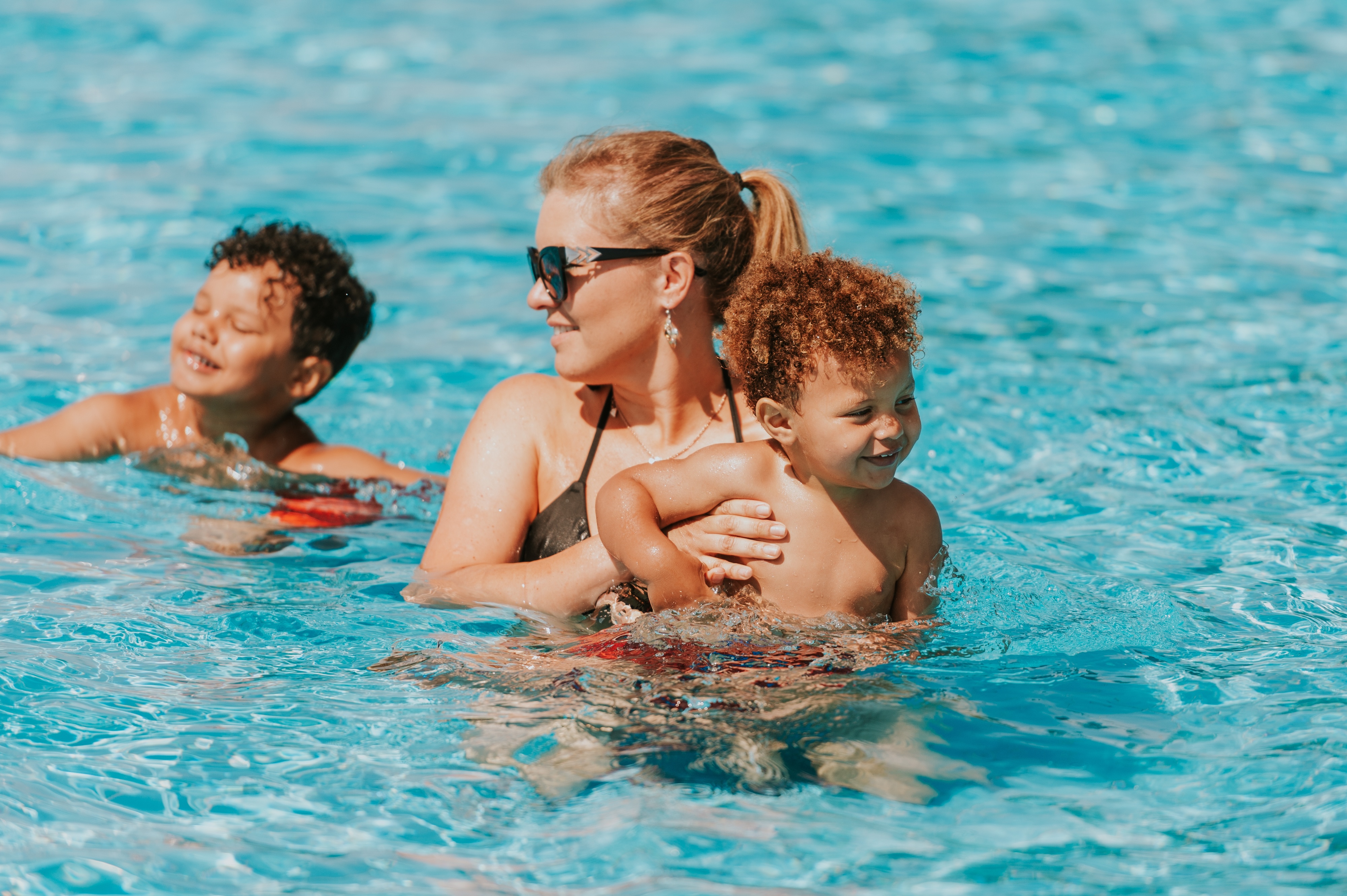 Mother and sons in swimming pool stock photo