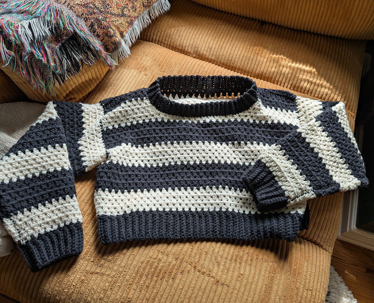 a black and white striped sweater laying causally on a mustard yellow couch