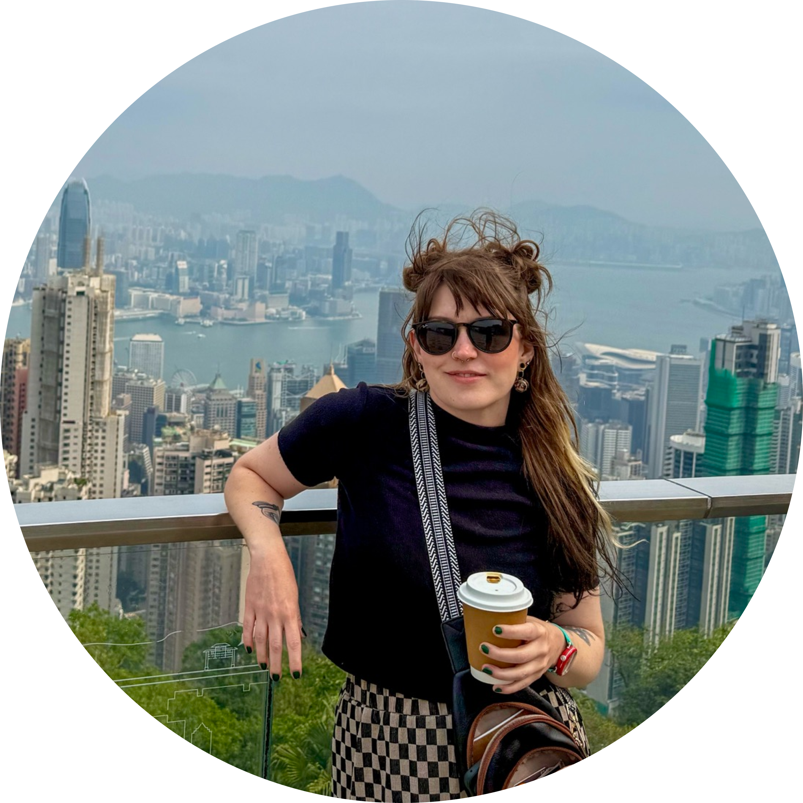 A woman leaning on a railing high above a the city of Hong Kong behind her