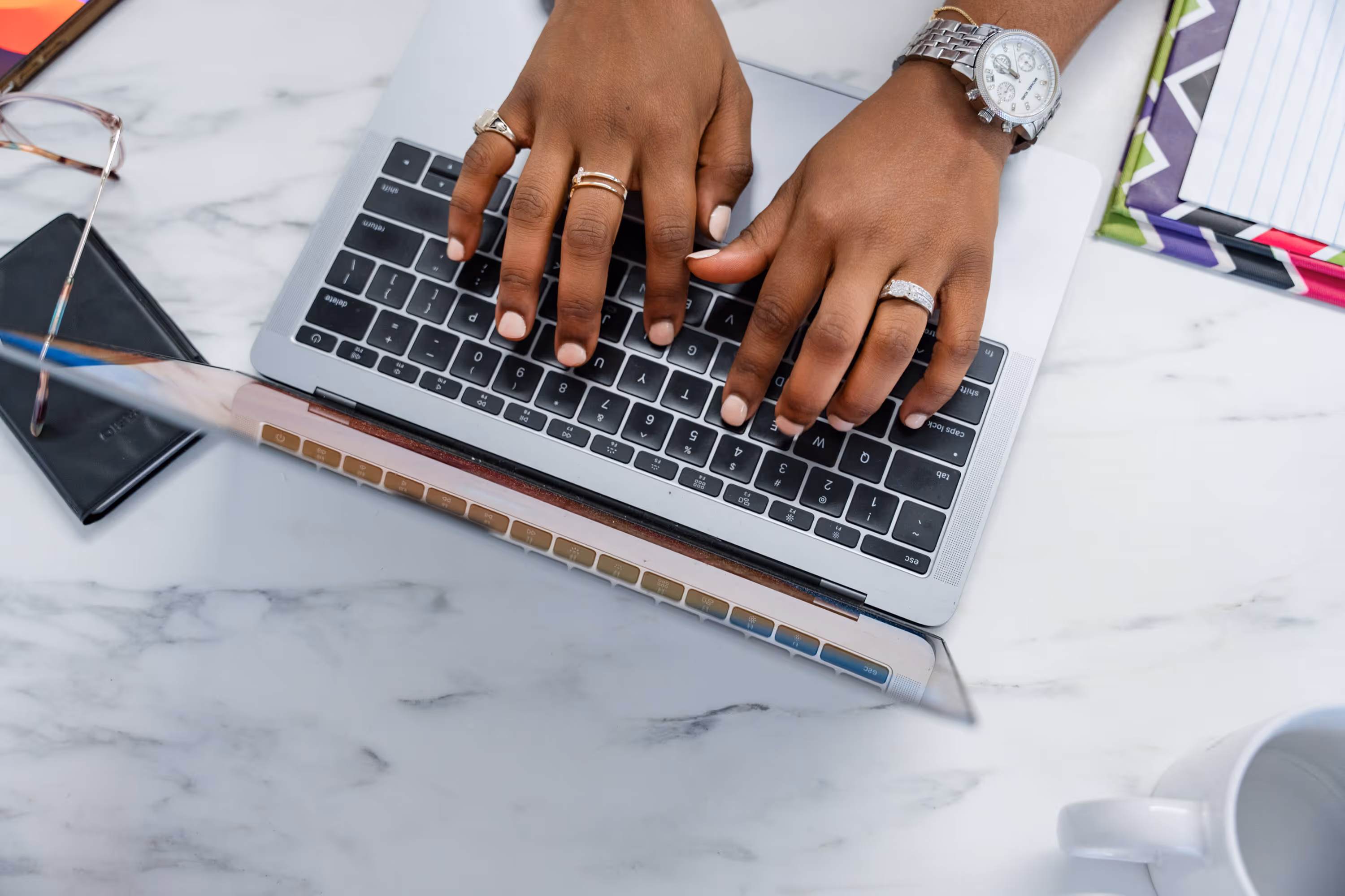Close-up top-down view of accountant Chrystal Bonney’s hands typing on a laptop keyboard at her workspace.