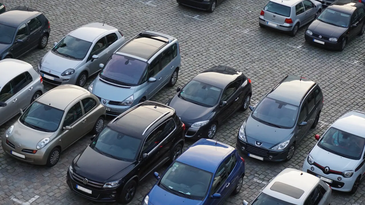 Overhead view of various compact cars parked on a cobblestone surface in a parking lot.
