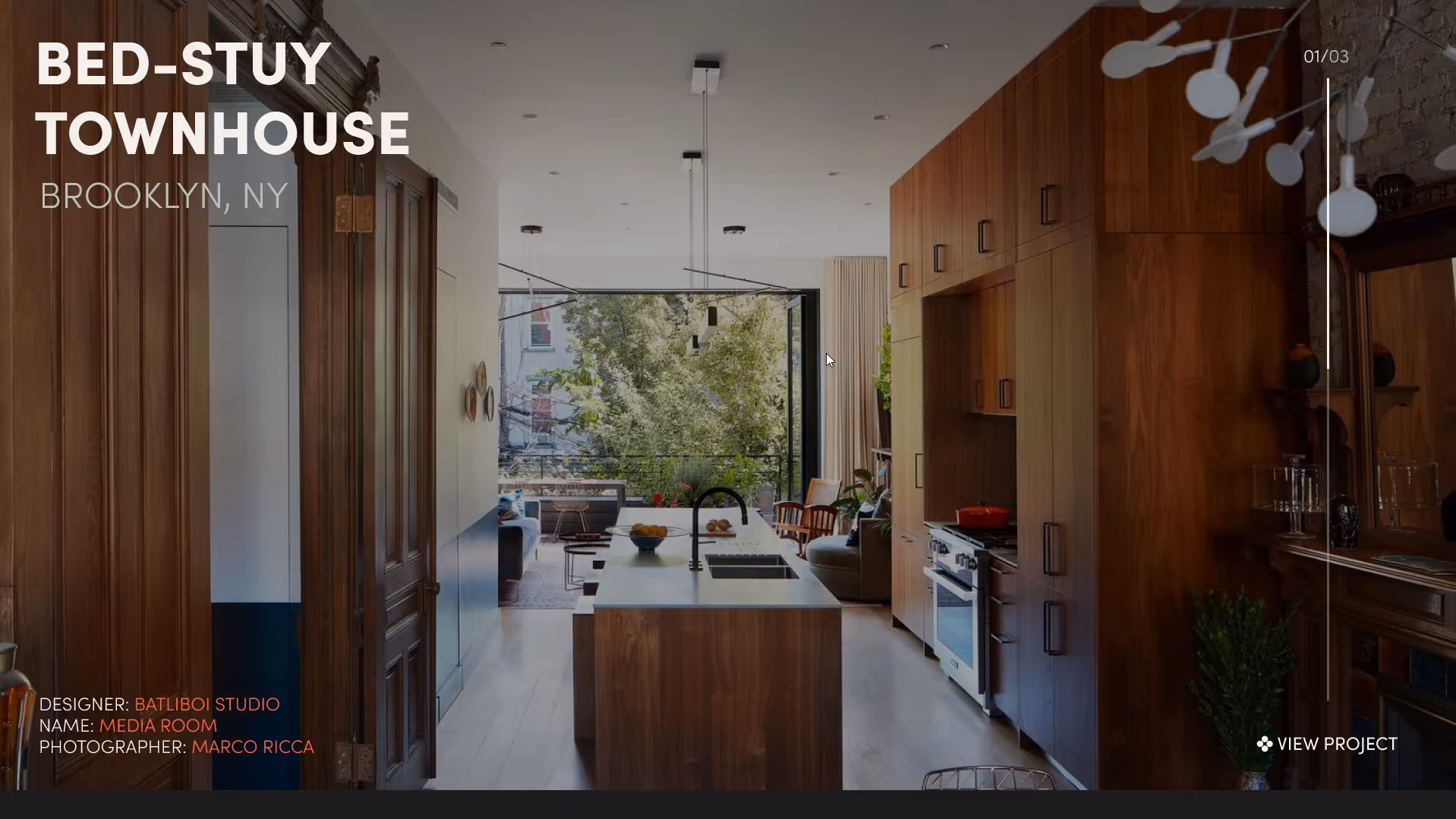 Modern townhouse kitchen with wooden cabinetry, central island, and large open window overlooking greenery.