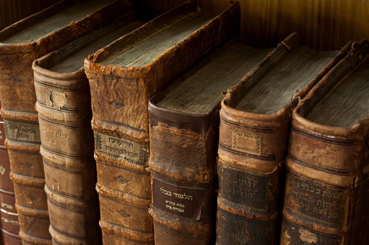 A row of old leather-bound Hebrew volumes on a shelf