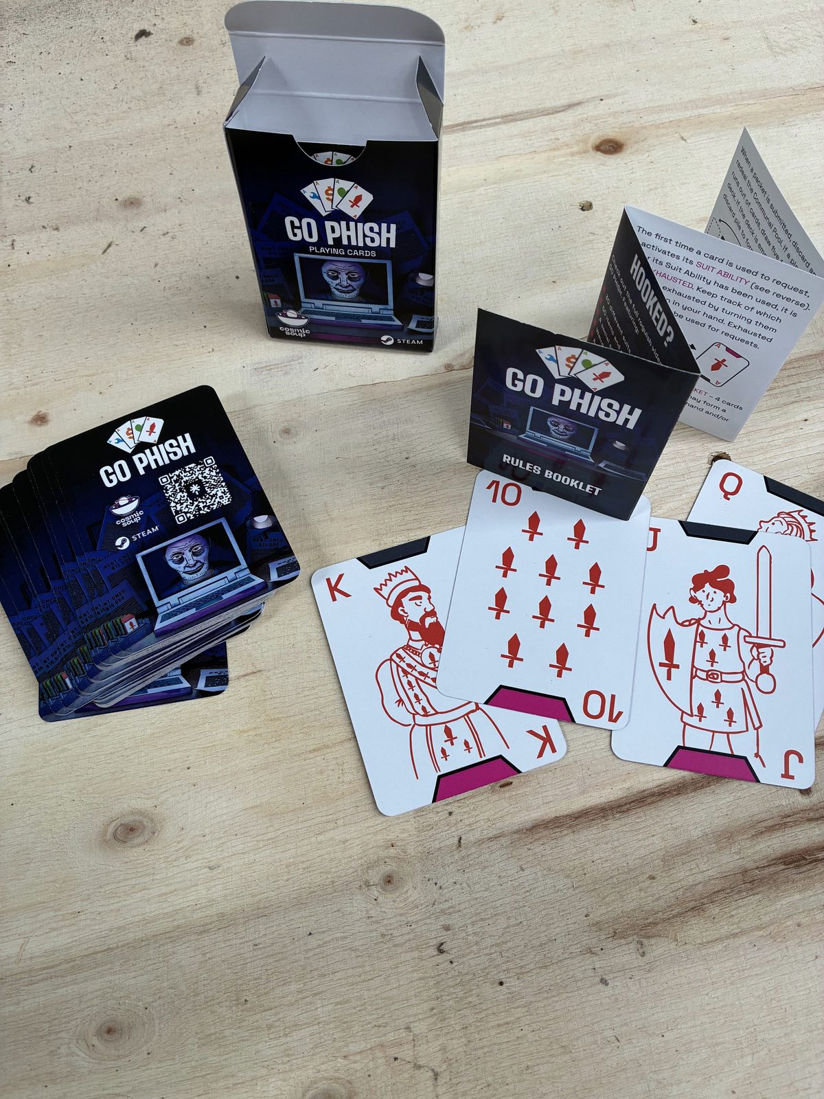 Go Phish playing card deck printed in New Zealand for Cosmic Soup Games, showing the printed tuck box, folded rules booklet and court cards with custom phishing suit symbols