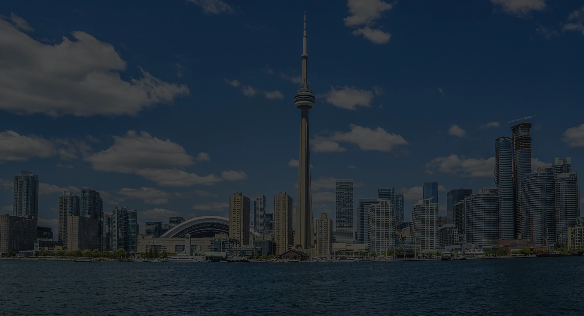 Toronto city skyline with the CN Tower under a blue sky with scattered clouds.