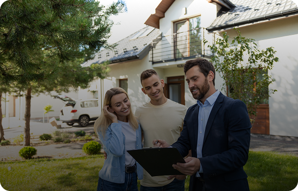 Real estate agent showing a clipboard to a young couple standing outside a house on a sunny day.