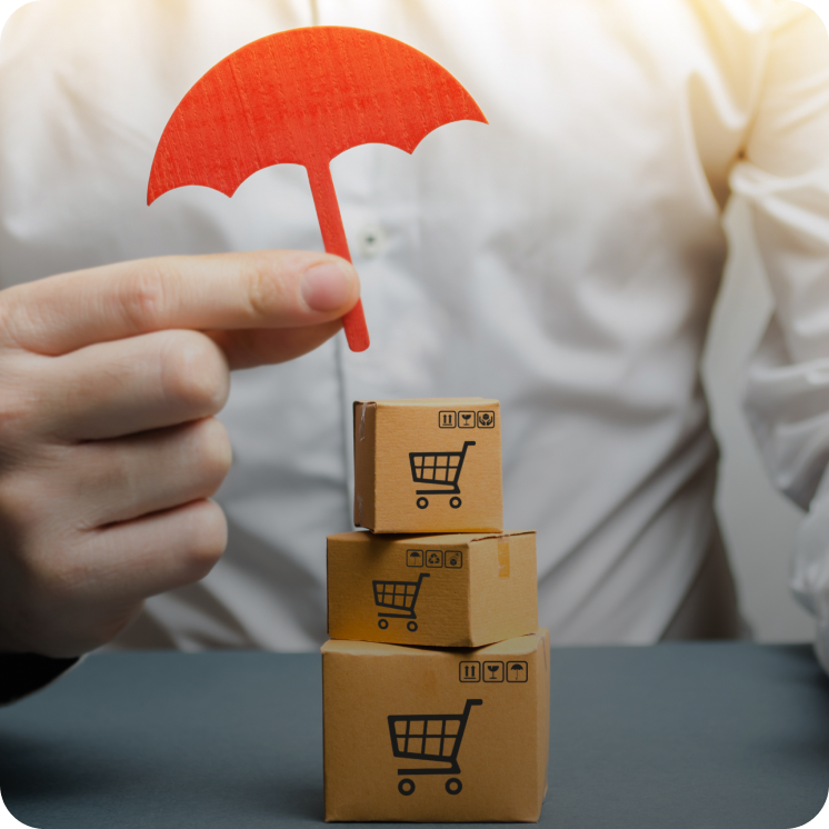 Person holding a small red paper umbrella over a stack of three cardboard boxes with shopping cart icons.