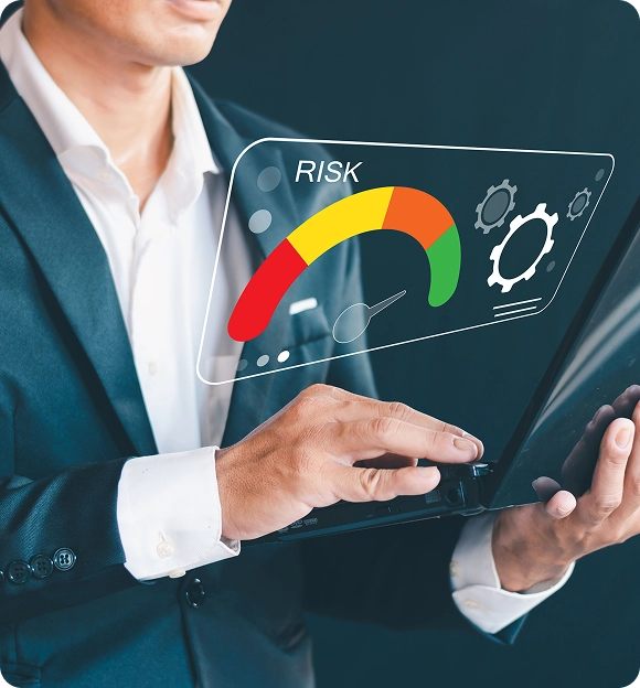 Man in suit interacting with a laptop showing a digital risk meter with red, yellow, orange, and green sections and gear icons.