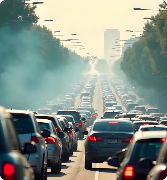 Heavy traffic congestion on a multi-lane road with visible exhaust smoke and streetlights lining both sides.