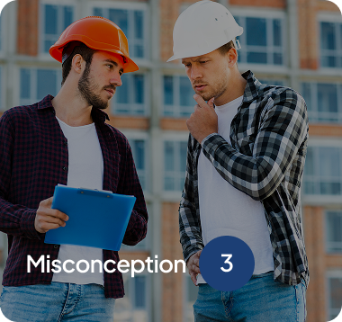 Two construction workers wearing hard hats reviewing a clipboard outside a building under construction.