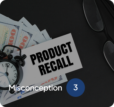 Table with hundred-dollar bills, an alarm clock, eyeglasses, and a card labeled 'Product Recall' on a dark surface.