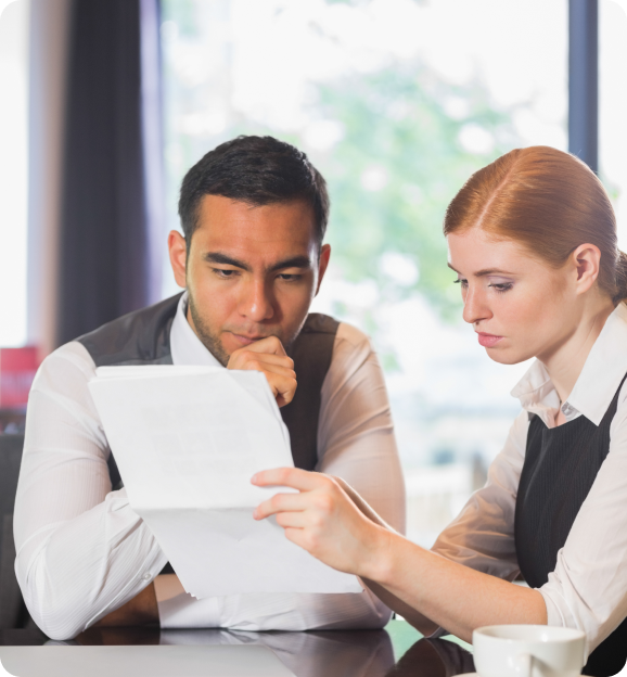 Two business professionals focused on reviewing a document together at a table.