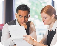 A man and woman reviewing documents together in a well-lit office.