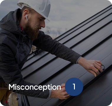 Man wearing a white hard hat and dark jacket inspecting a black metal roof panel.