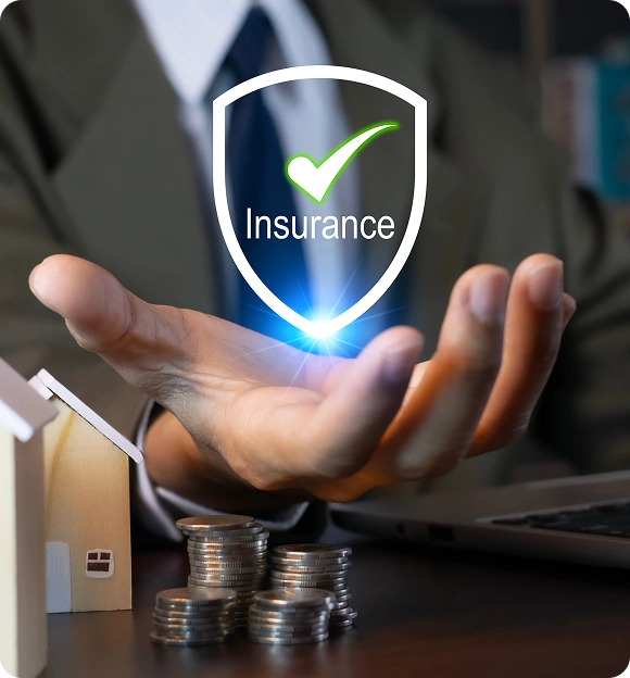 Businessman holding a holographic shield with a green checkmark and the word 'Insurance' above stacks of coins and a small wooden house model on a desk.
