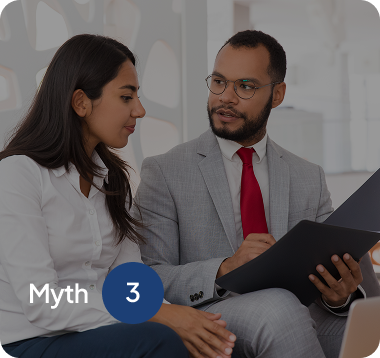 A man in a gray suit and red tie holding a folder discussing with a woman in a white blouse indoors.